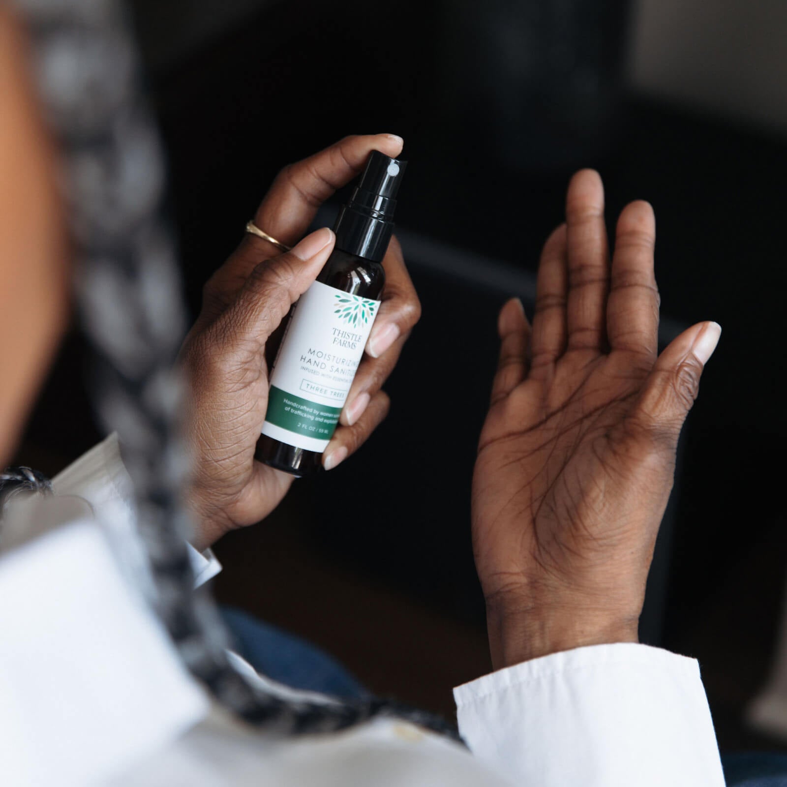 Person spraying a hand sanitizer bottle with a dark background