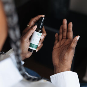 Person spraying a hand sanitizer bottle with a dark background