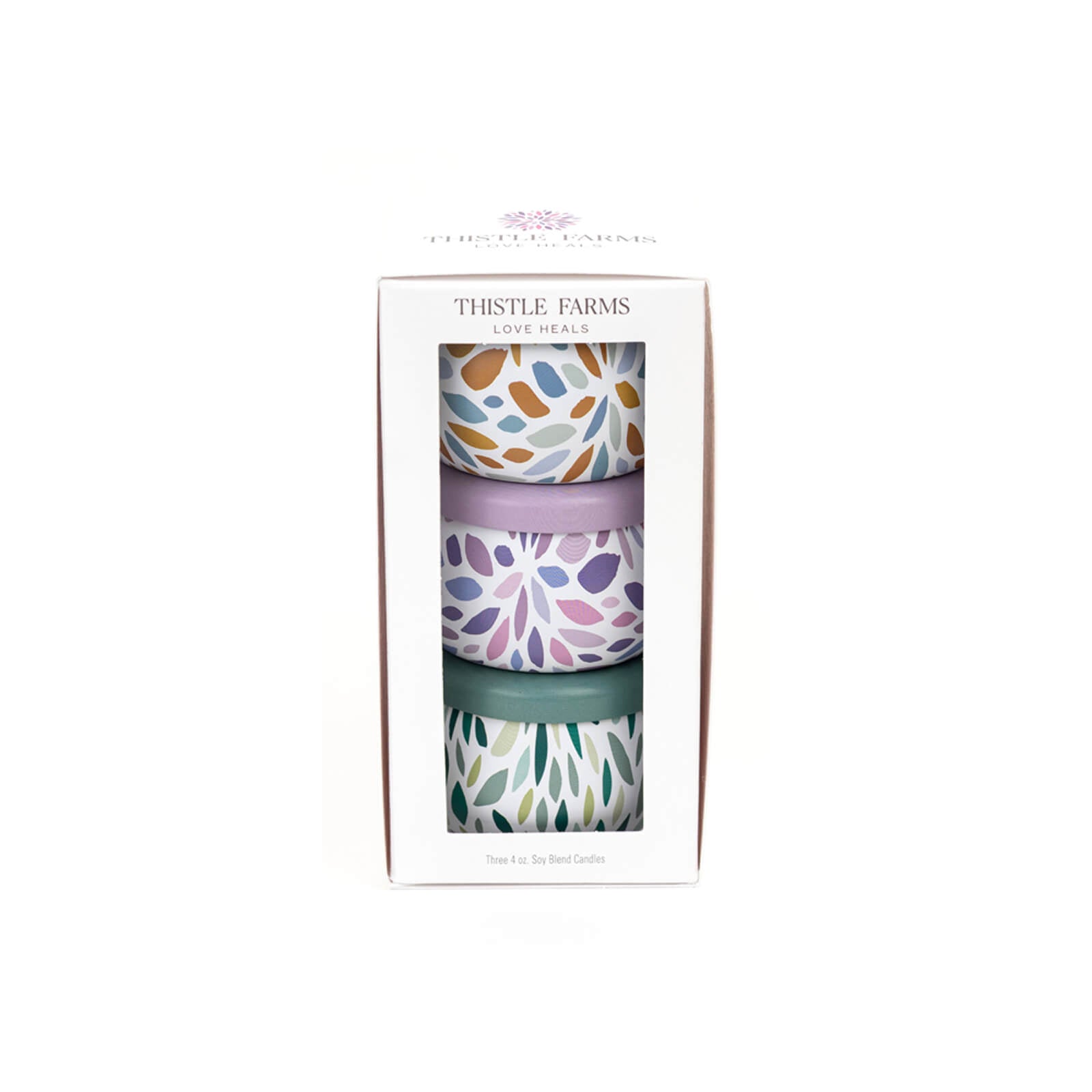 Three patterned candles in a box with 'Thistle Farms' branding on a white background