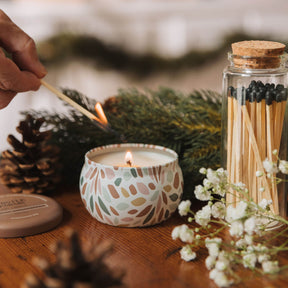 Candle being lit with a match, surrounded by decorative elements on a wooden surface.