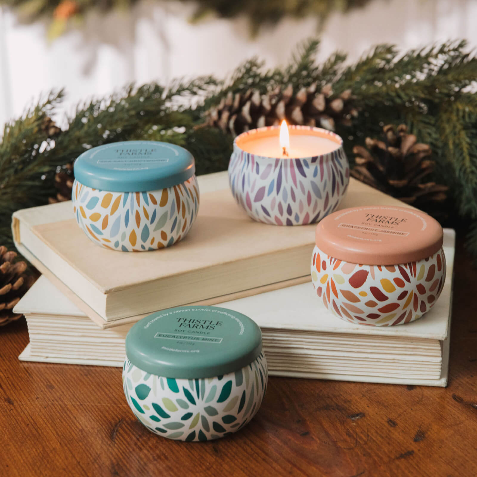 Four patterned candles on books with a blurred festive background