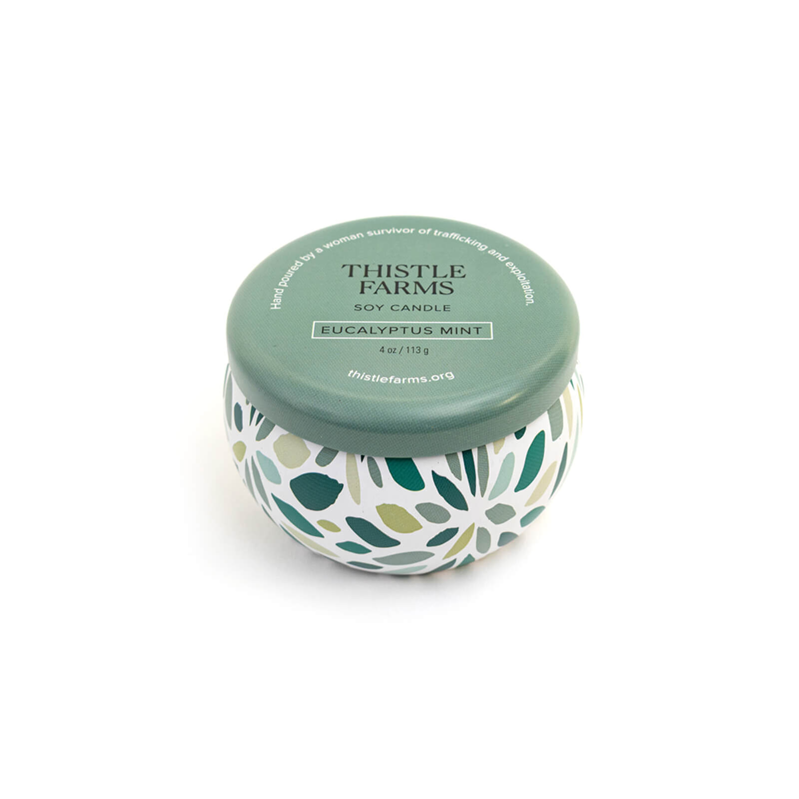 Thistle Farms soy candle with a green lid and a patterned base on a white background