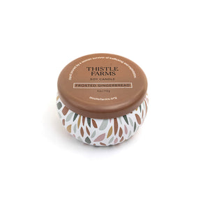 Thistle Farms soy candle with a brown lid and a patterned base on a white background