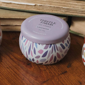 Thistle Farms soy candle with a patterned design on a wooden surface