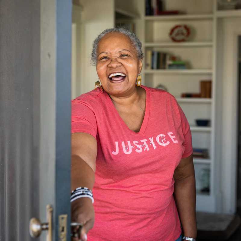 Woman smiling at a door wearing a "justice" tshirt